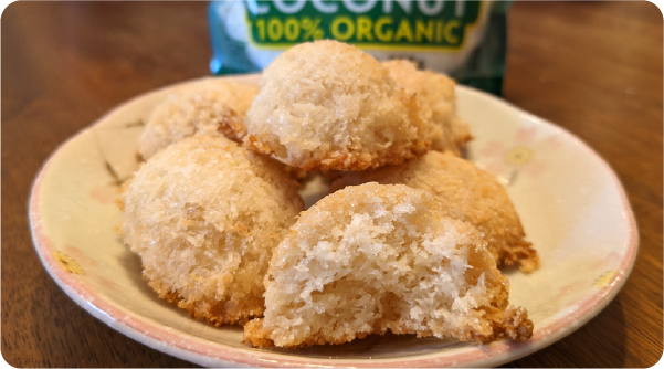 Coconut macaroons on a small plate with one broken open to show the soft coconut center